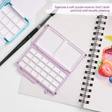 Mini palette de mélange d'aquarelle Fuumuui en violet doux, ouverte pour révéler 24 godets et plateaux de mélange doubles pour la peinture portable, montrée avec un pinceau Fuumuui et une palette bleue sur un carnet de croquis d'art.