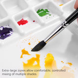 Palette d'aquarelle professionnelle Fuumuui à 47 godets avec un pinceau mélangeant de la peinture jaune sur sa surface antiadhésive extra-large, présentant plusieurs couleurs vibrantes dans les godets pour Fuumuui Art Supplies.