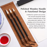 Fuumuui professionelle Kalligraphie- und Aquarellpinsel mit polierten Holzgriffen, natürlichen weißen Borsten und funktionalen Aufhängeschnüren, ideal für die Tuschemalerei, ausgestellt auf einer Bambusmatte mit roter Tinte.
