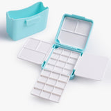 Boîte de palette d'aquarelle pliante double couche Fuumuui en bleu clair, ouverte pour montrer 24 godets et 7 zones de mélange, avec un porte-pinceau portable assorti. Fournitures d'art Fuumuui compactes pour les voyages et l'utilisation en studio.