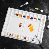 Palette d'aquarelle professionnelle Fuumuui à 47 godets, une fourniture d'art en plastique antiadhésif blanc pour mélanger les peintures, remplie de couleurs vibrantes et d'un pinceau.