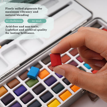 Mano che tiene una vivace cialda rossa da un set di acquerelli portatile a 50 colori Fuumuui, che mostra pigmenti finemente macinati, privi di acidi e resistenti alla luce per la massima vivacit¨¤, miscelazione naturale e brillantezza duratura senza gesso o fango.