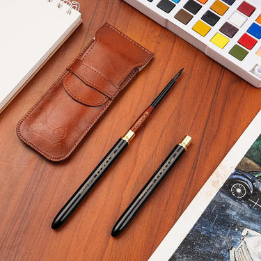 Fuumuui Set da 4 pezzi di pennelli da viaggio in pelo di scoiattolo per acquerello, tra cui un pennello assemblato e un pennello con cappuccio in una custodia in pelle marrone, accanto a una tavolozza di colori ad acquerello.