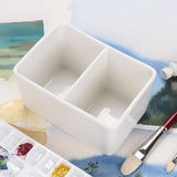 Fuumuui weißes Zweikammer-Keramik-Pinselwaschbecken, perfekt für Aquarell- und Acrylmalerei, gezeigt mit einem Pinsel und einer Palette.