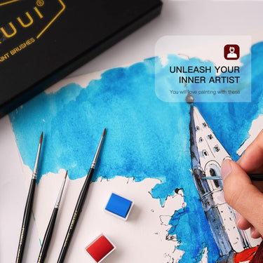 Fuumuui 5er-Set professionelle Kolinsky Zobel Detailpinsel im Einsatz, die Hand eines Künstlers malt präzise eine architektonische Aquarellzeichnung. Weitere feine Detailpinsel und Farbpfännchen von Fuumuui liegen auf dem Zeichenpapier.