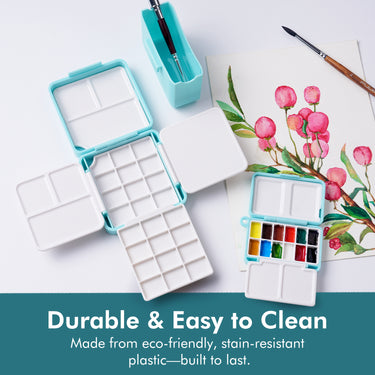 Boîte de palette d'aquarelle pliante double couche Fuumuui, ouverte montrant 24 godets et 7 zones de mélange, à côté d'un plateau de peinture compact de fournitures d'art Fuumuui rempli d'aquarelles vibrantes, une peinture et des pinceaux pour une utilisation en studio et en voyage.