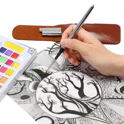 Fuumuui 3pcs Nylon Travel Watercolor Brushes. A hand paints intricate details with a Fuumuui travel watercolor brush, next to a colorful watercolor palette and the brush set's protective leather case.