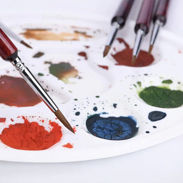 Fuumuui Detailpinsel, der in Farbe auf einer Farbpalette getaucht wird, ein vielseitiges Werkzeug zum Erstellen von Miniaturkunst und detaillierten Aquarellmalereien.