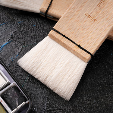 A close-up of a Fuumuui 40mm wool watercolor brush, featuring extra soft, high absorption bristles and a natural bamboo handle, perfect for washes, backgrounds, and large area painting.