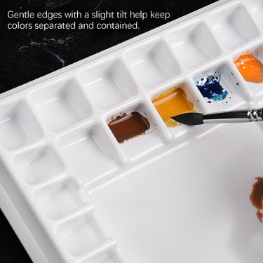 Palette d'aquarelle professionnelle Fuumuui à 47 godets montrant des godets en plastique antiadhésifs avec des bords doux et inclinés contenant de la peinture jaune, bleue et marron, assurant une séparation des couleurs anti-déversement avec un pinceau d'art.