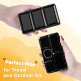 Fuumuui Travel Watercolor Set palette in hands, showing compact black design with mixing wells and finger ring, ideal for 12 watercolors and outdoor art.