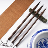 Fuumuui Professional Calligraphy Brushes: Three dark bamboo section brushes with pointed tips, suitable for watercolor, displayed on a green jade brush rest.