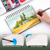 Fuumuui Watercolor Sketchbook, spiral bound, 100% cotton, showing excellent water absorption and wrinkle-resistant paper as an artist paints a landscape with Fuumuui art supplies.