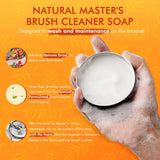 Fuumuui Pinselreiniger-Seife, 100% vegan, in einer silbernen Dose, die von einer schaumigen Hand gehalten wird, die ihre Fähigkeit demonstriert, getrocknete Farbe zu entfernen und Künstlerpinsel zu pflegen.