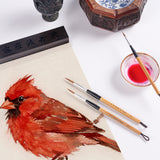 Fuumuui Wolfshaar-Kalligraphiepinsel (3er-Set) mit natürlichen Bambusgriffen und Messingzwingen, die neben einem lebendigen Aquarellbild eines roten Kardinalvogels gezeigt werden und die Fuumuui-Kunstmaterialien hervorheben.