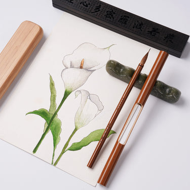FUUMUUI Handgefertigter Tierhaarkalligraphiepinsel mit Magnetkappe und eleganter Geschenkverpackung, ausgestellt mit einer Jade-Pinselablage und einem Aquarellgemälde von weißen Calla-Lilien.