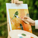 Fuumuui Palette Knife Painting set: Hand using a #5 stainless steel palette knife with a wood handle to apply oil or acrylic paint on canvas, with a paint spatula palette for color mixing.