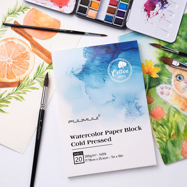 Fuumuui Watercolor Block 7x10 inch 100% Cotton Cold Press paper, central to an artist's setup with Fuumuui watercolor paints, brushes, and vibrant finished artwork.