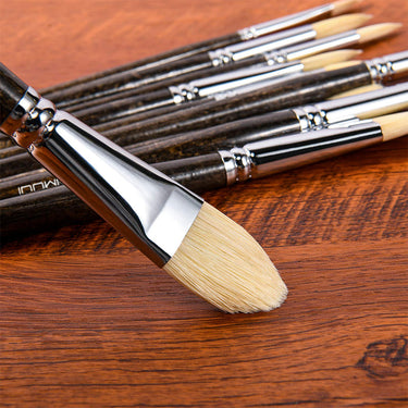 Fuumuui 11pcs professional natural hog bristles paint brush set. Close-up of light cream bristles, silver ferrule, and dark wooden handles on a wood surface.