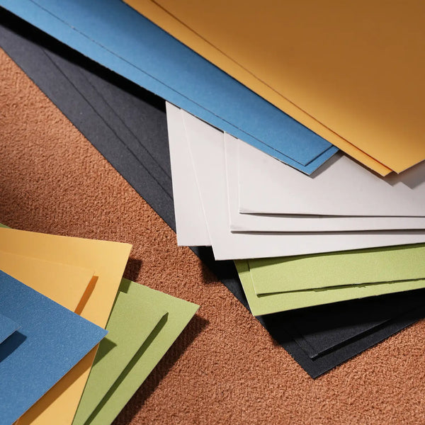 Assorted multi-colored textured pastel paper sheets in blue, yellow, white, and green, designed for professional artists and beginners using soft pastels, oil pastels, and charcoal on high-quality art paper.
